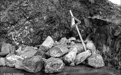 blocs de pierres écroulés sur un panneau attention chutes de pierres